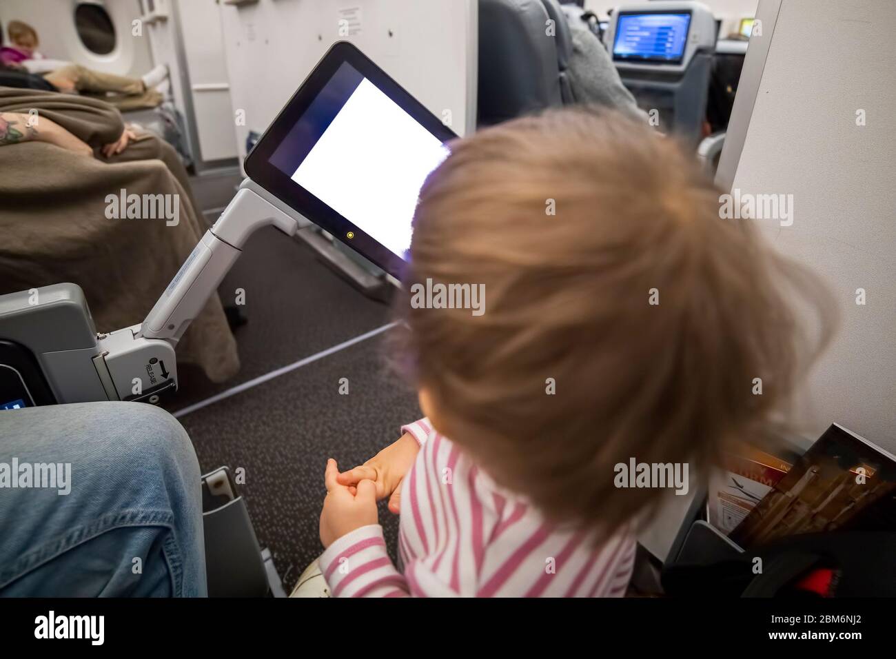 Unterhaltung an Bord des Flugzeugs. Kind, das auf weißen Bildschirm des Copyspace-Flugzeuges Multimedia-System schaut. Stockfoto