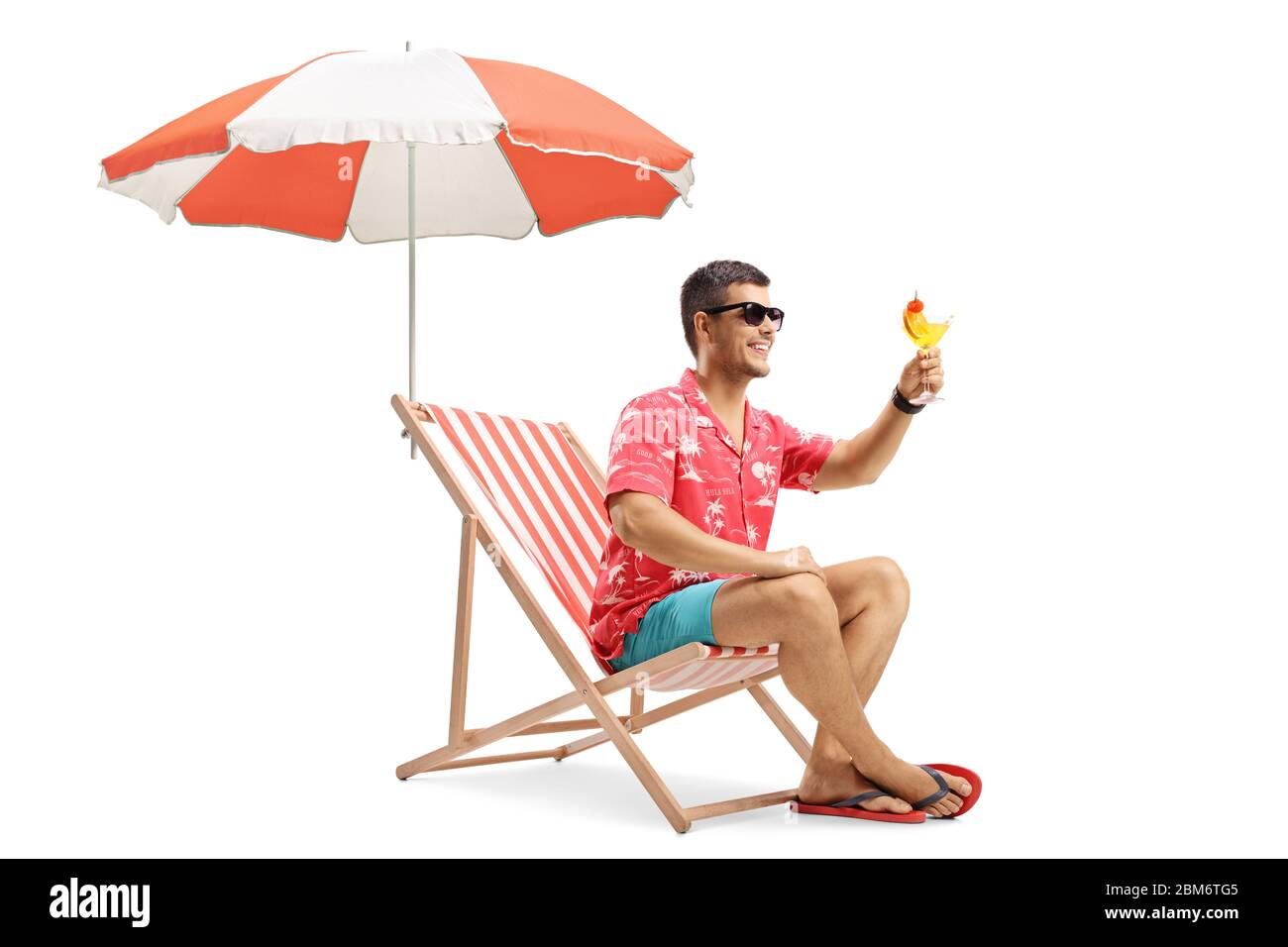 Junger Mann, der mit einem Cocktail unter einem Sonnenschirm auf weißem Hintergrund angestoßen wird Stockfoto