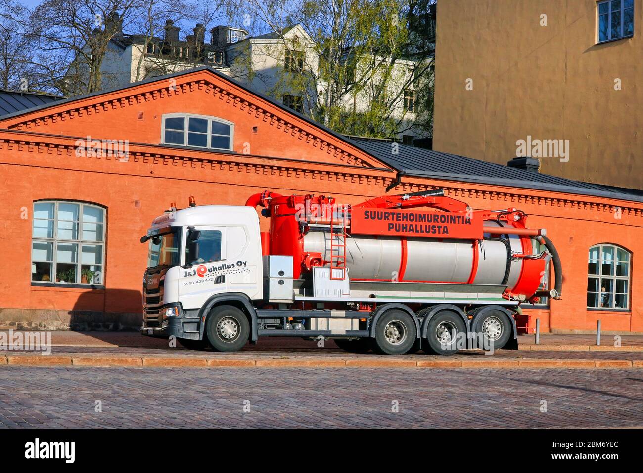 Weißer Scania Vakuum- und Drucktank-LKW von J&J Puhallus Oy, der auf der Straße im Stadtverkehr im Morgenlicht fährt. Helsinki, Finnland. Mai 2020. Stockfoto