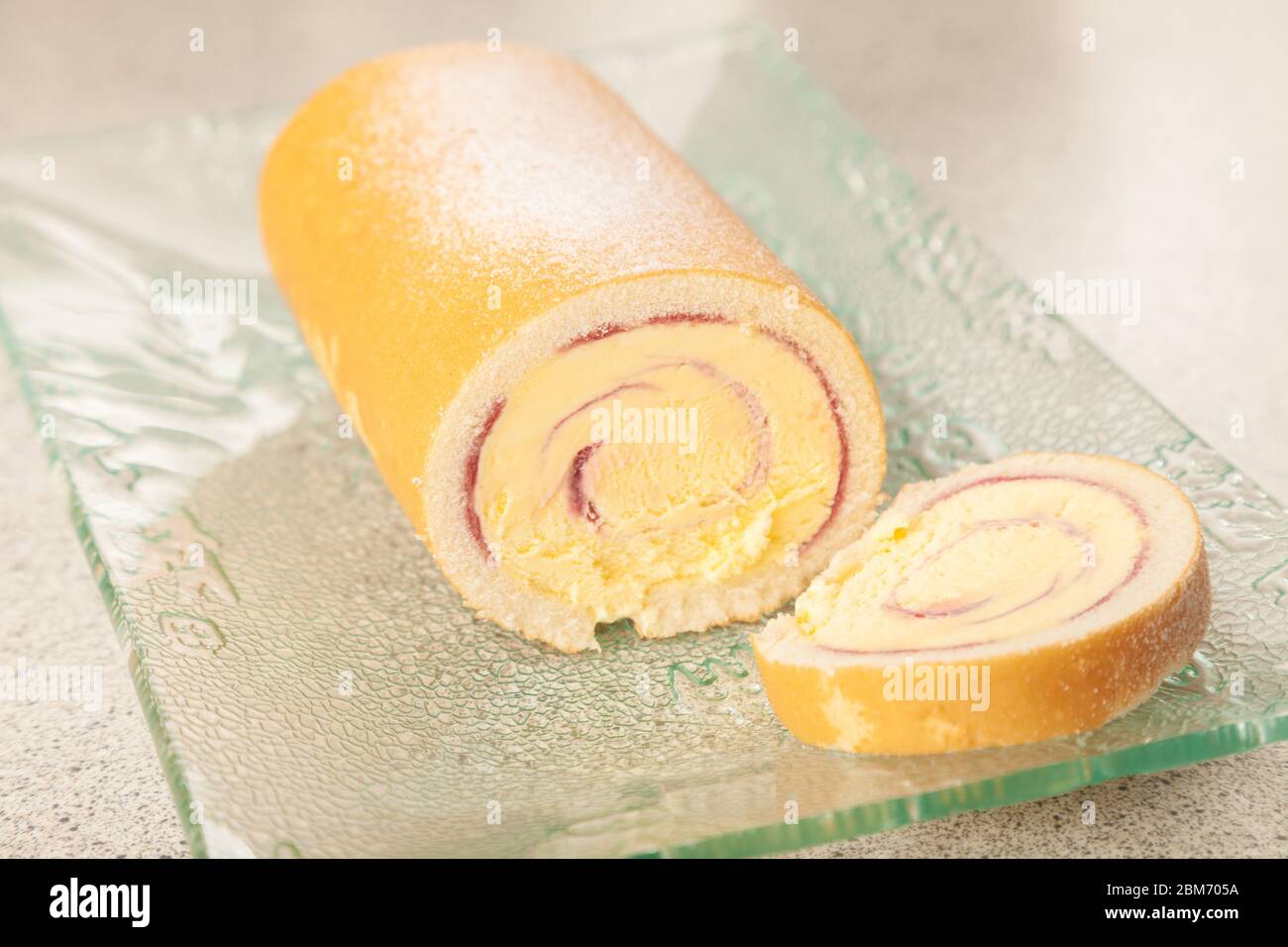 Eine geschnittene Arctic Roll gefrorene Wüste mit Gießzucker auf einem Glas Servierteller bestäubt. Stockfoto