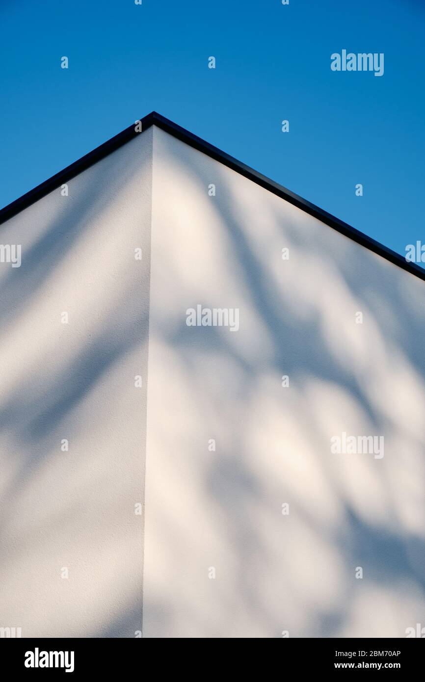 Abstrakte Architektur Aufnahme von zwei Wänden und einer Ecke eines modernen Hauses mit weißem Putz gegen klaren blauen Himmel. Gesehen in Deutschland im März. Stockfoto
