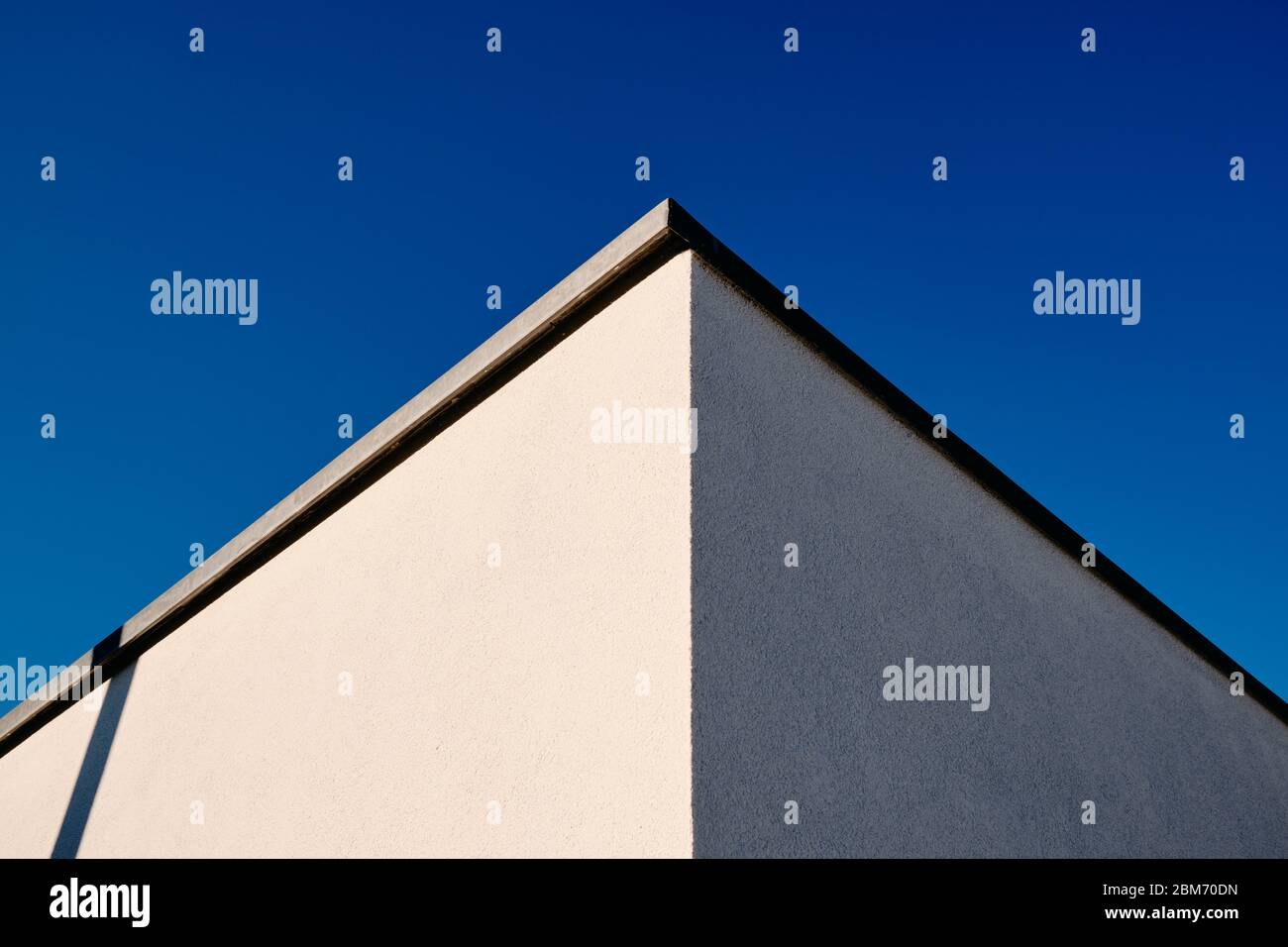 Abstrakte Architektur Aufnahme von zwei Wänden und einer Ecke eines modernen Hauses mit weißem Putz gegen klaren blauen Himmel. Gesehen in Deutschland im März. Stockfoto