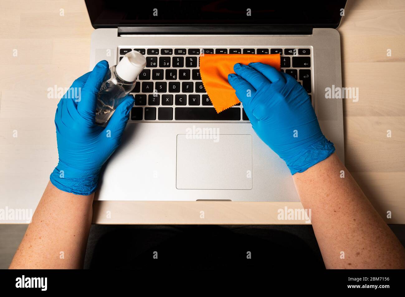 Coronavirus-Prävention. Laptop mit Desinfektionsspray und Handschuhen reinigen und desinfizieren. Notebook-Computeroberflächen vor Viren reinigen, Stockfoto