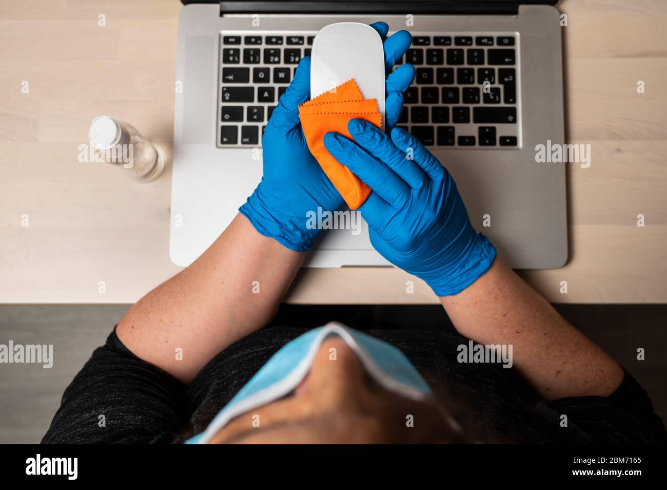 Unkenntlich Frau mit Schutzmaske Reinigung und Desinfektion einer Maus. Reinigen der Oberflächen von Notebook-Computern von Viren, Mikroben und Schmutz Stockfoto