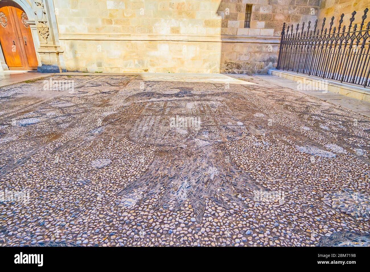 GRANADA, SPANIEN - 27. SEPTEMBER 2019: Der Steinboden an der Wand der Capilla Real (Königliche Kapelle) ist mit dem spanischen Emblem, Calle Oficios (La Lo Stockfoto