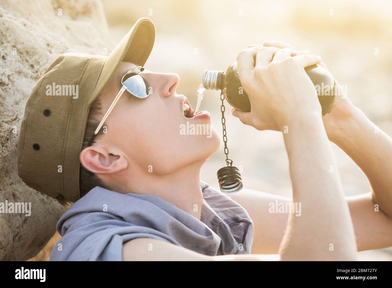 Mann mit Flasche in der Wüste. Dürre und Wasserknappheit durch die globale Erwärmung Stockfoto