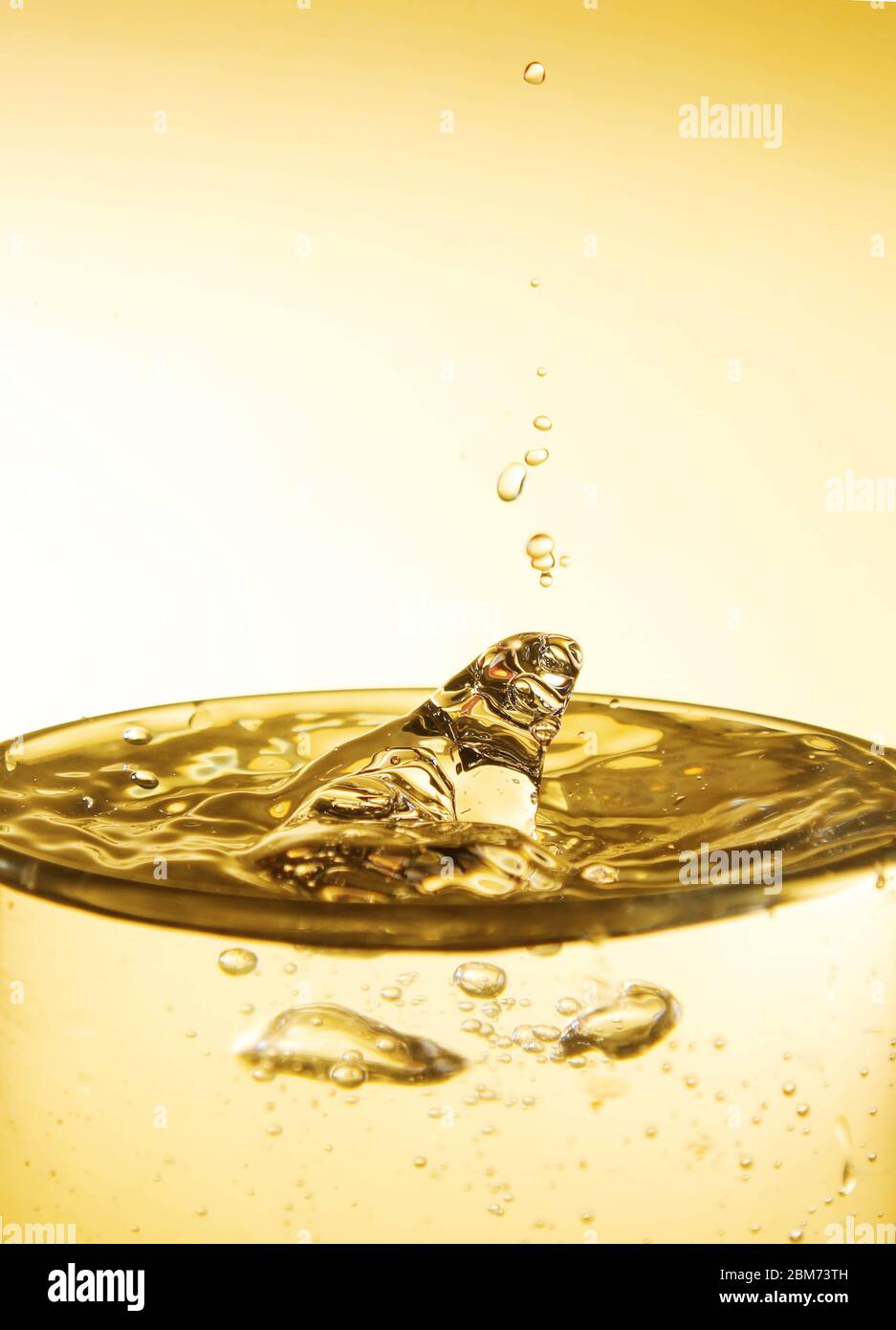 Wassertropfen auf Wasseroberfläche in einem Glas auf gelbem Hintergrund Stockfoto