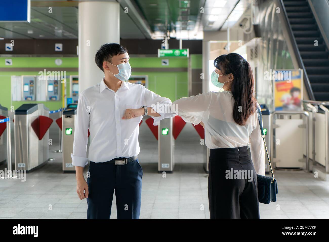 Ellenbogenschlag ist eine neue neue Begrüßung, um die Ausbreitung von Coronavirus zu vermeiden. Zwei asiatische Wirtschaftsfreunde treffen sich in der U-Bahn-Station. Statt mit einer Umarmung zu grüßen Stockfoto