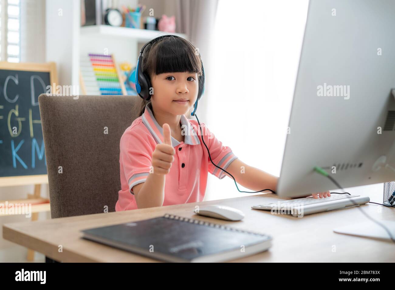 Asiatische Student Mädchen Videokonferenz E-Learning mit Lehrer auf Computer und Daumen nach oben im Wohnzimmer zu Hause. E-Learning, online, Bildung und intern Stockfoto