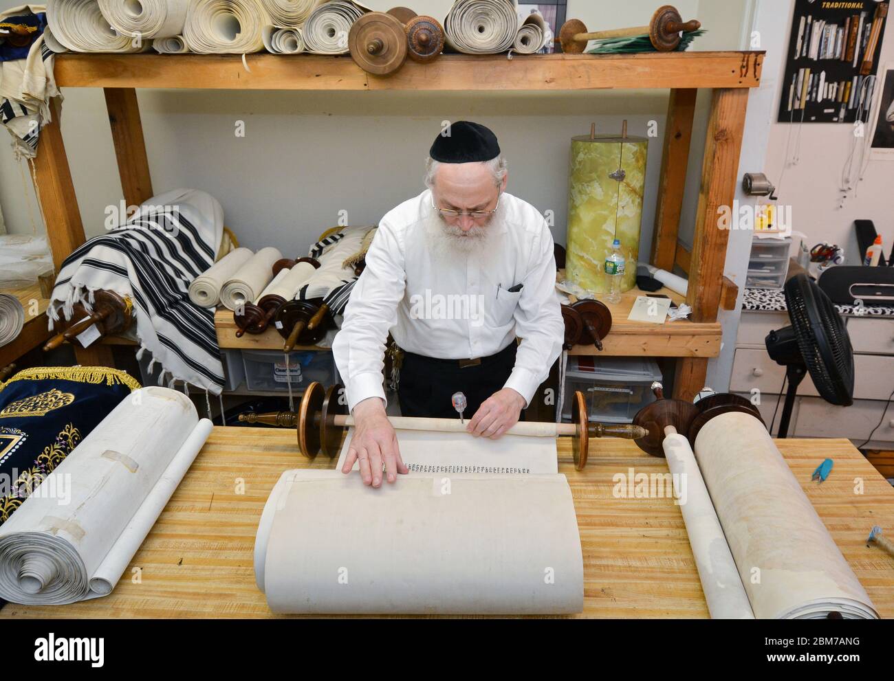Ein Rabbiner bereitet das Nähen einer reparierten Torah auf ihre Holzgriffe in einem Geschäft in Brooklyn, New York, vor. Stockfoto