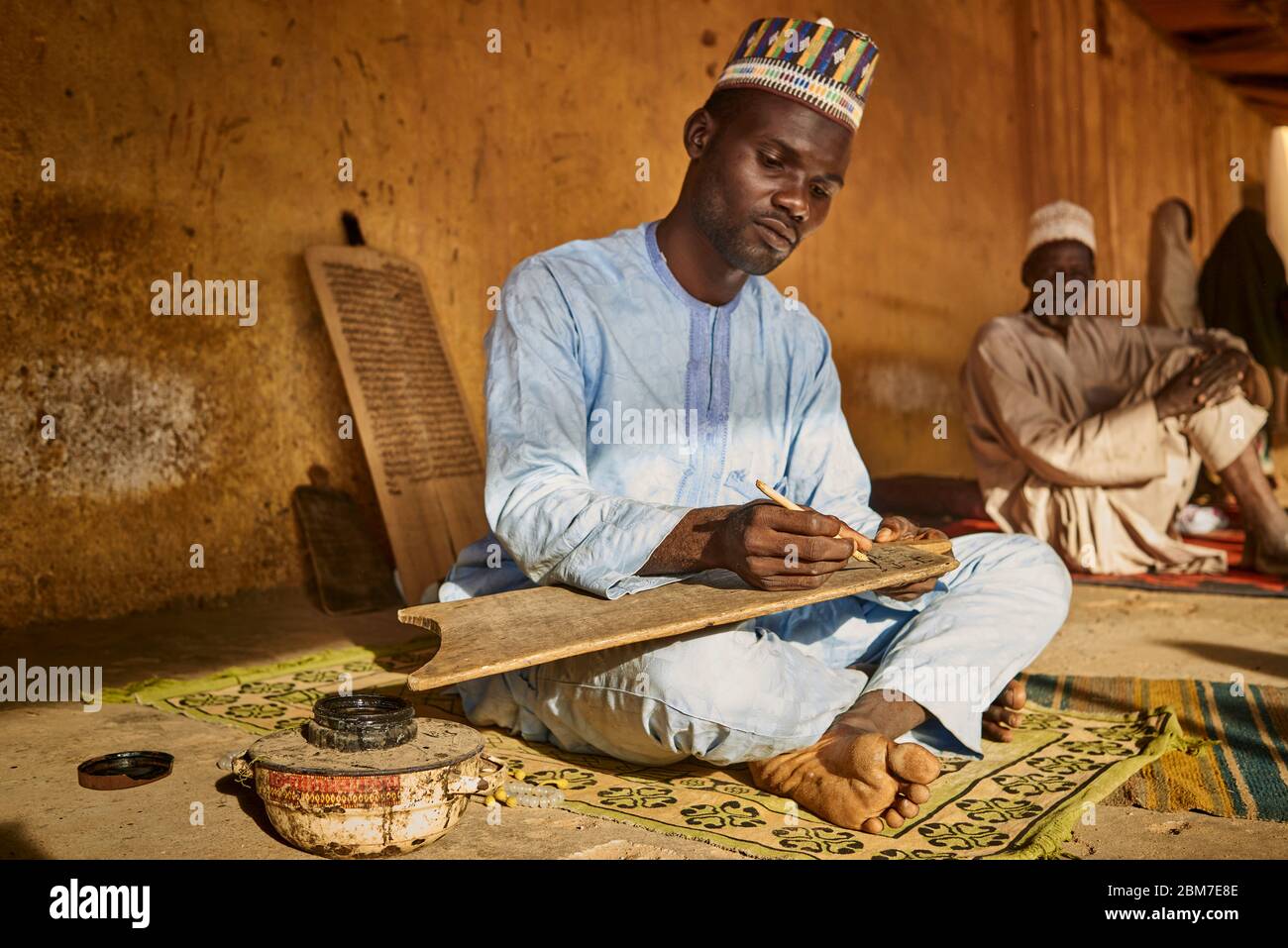 Muslimischer Mann, der korankalligraphie auf einer Holztafel praktiziert. Stockfoto