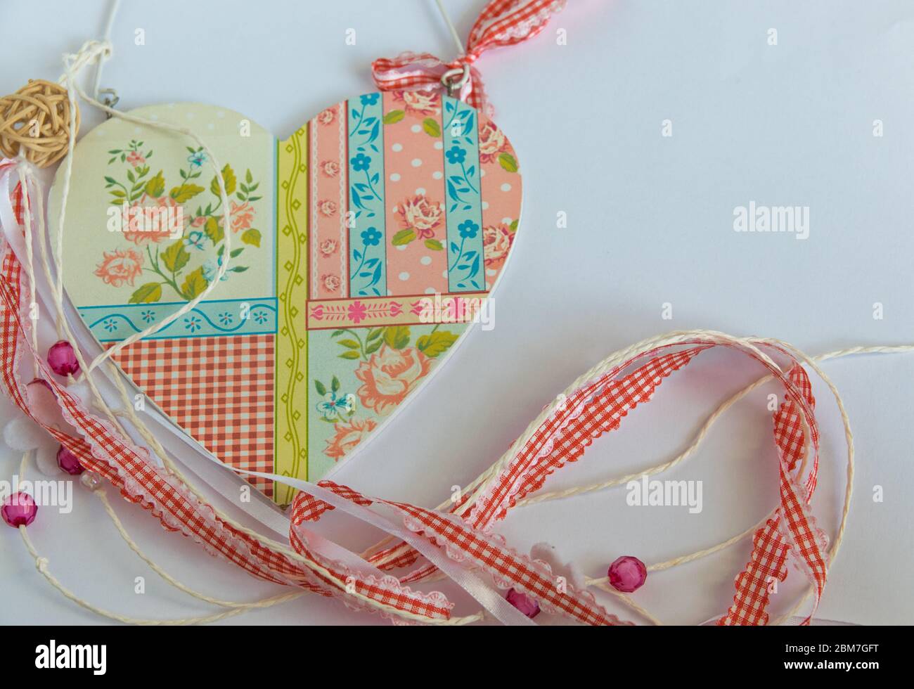 Holz schönes Herz mit Ornament, Bänder, Perlen auf dem weißen Hintergrund. Flaches Lay. Handgefertigtes Konzept. Liebeszeichen für Valentinstag. Stockfoto