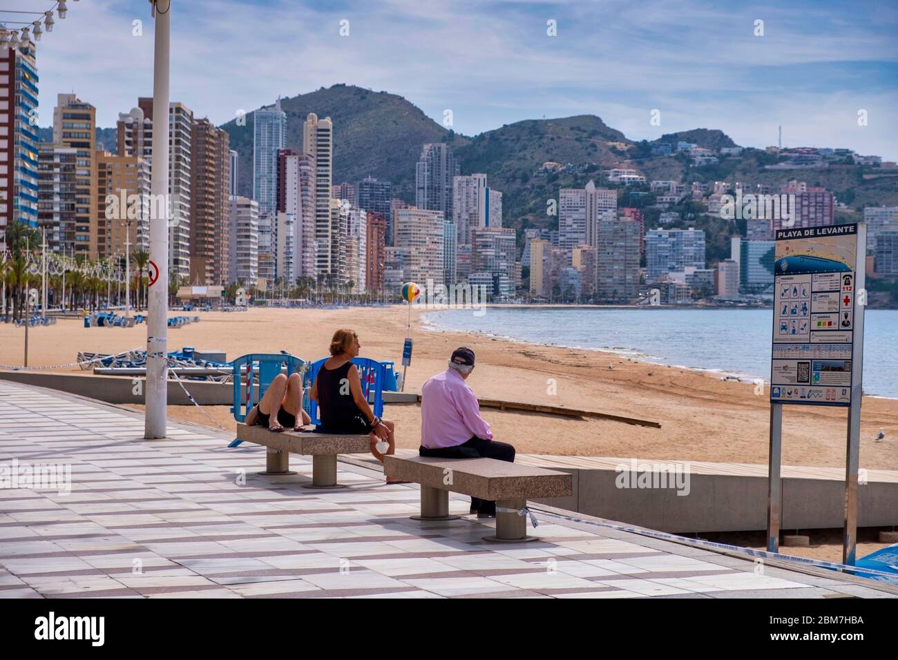 Benidorm, Alicante Spanien, 4.5.2020, Corona-Krise: Drei Leute sitzen und liegen auf Steinbänken an der Promenade am menschenleeren Strand Playa Levante Stockfoto