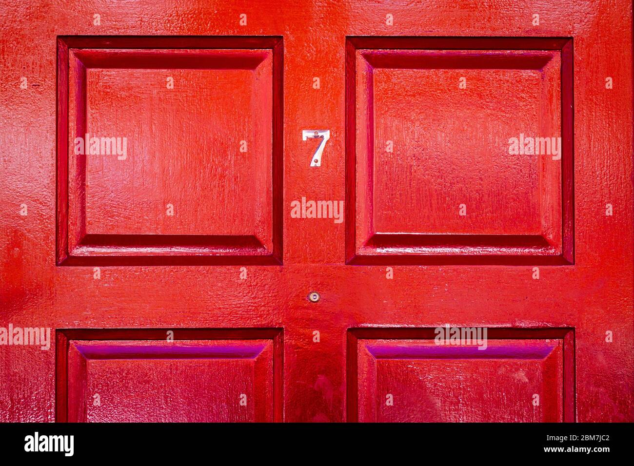 Haus Nummer 7 auf einer roten Holztür Stockfoto