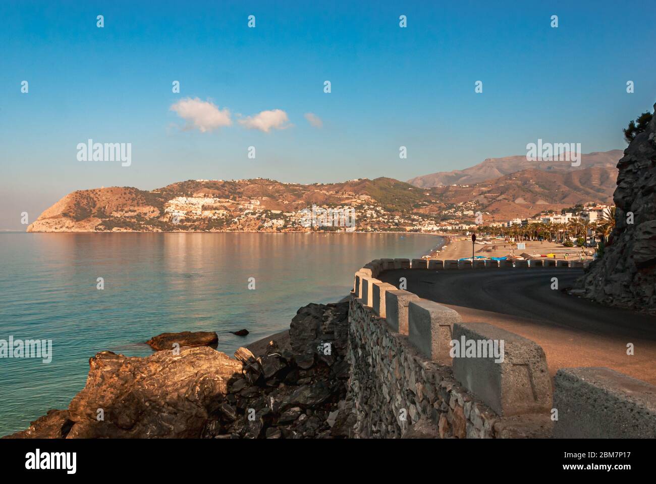 Küstenstraße, die zum Badeort La Herradura, Costa Tropical, Andalusien, Spanien führt, mit Blick auf das ruhige Wasser der Bucht an einem sonnigen Sommermorgen Stockfoto