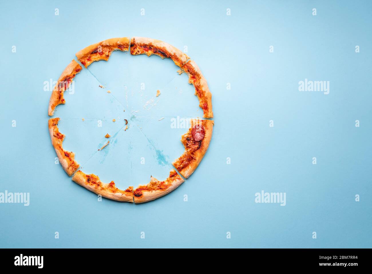 Pizza Pepperoni Reste von oben auf blauem Hintergrund. Hausgemachte Pizzabäcker und Fettspuren auf Karton Stockfoto