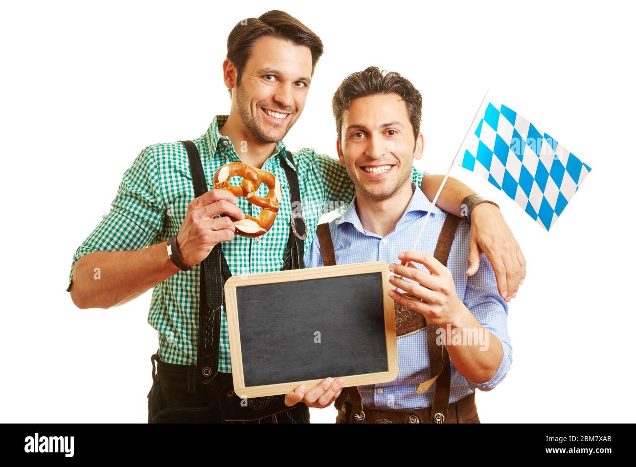 Zwei Männer in Lederhosen halten Brezeln und eine bayerische Flagge und eine Tafel Stockfoto