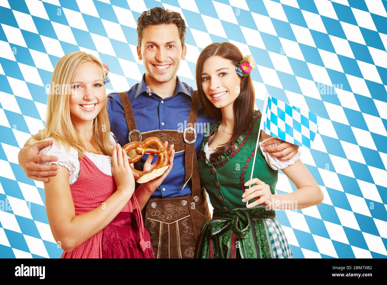 Lachender Mann und zwei lächelnde Frauen in bayerischer Tracht mit Dirndl und Lederhose Stockfoto