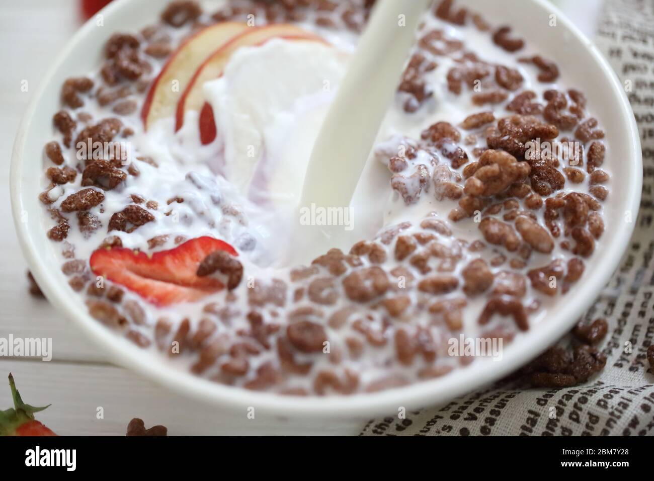 Milch wird in Schokoladenkugeln gegossen. Frühstückszerealien Stockfoto