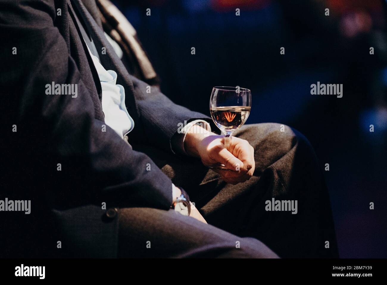 Mann hält Weinglas im Konzertsaal Stockfoto