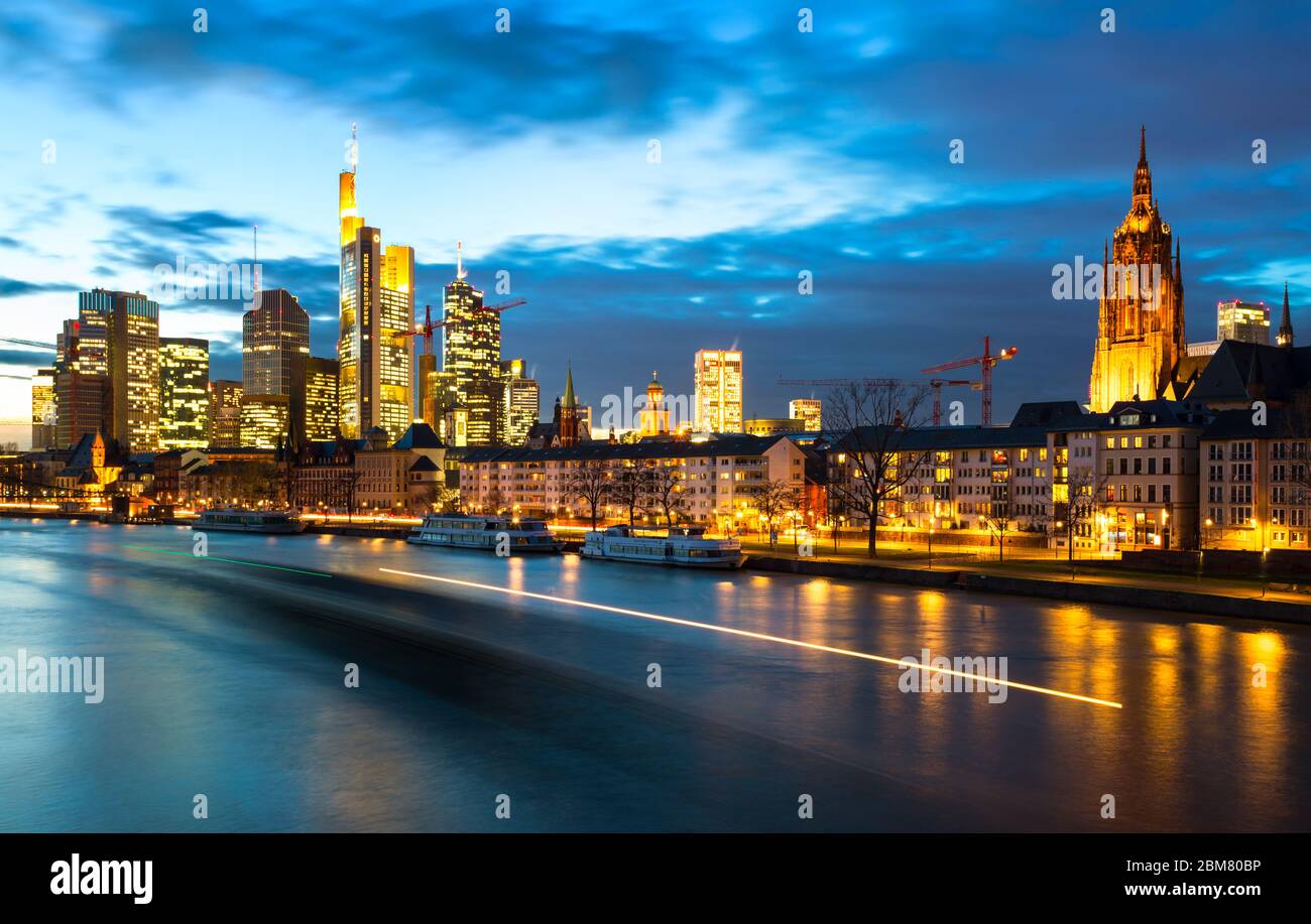 Dämmerung am Main als ein Lastkahn in Frankfurt am Main, Hessen, Deutschland vorbeifährt. Frankfurt ist die Metropole und größte Stadt des Landes Hessen und mit 746,878 (2017) Einwohnern die fünftgrößte Stadt Deutschlands. Stockfoto