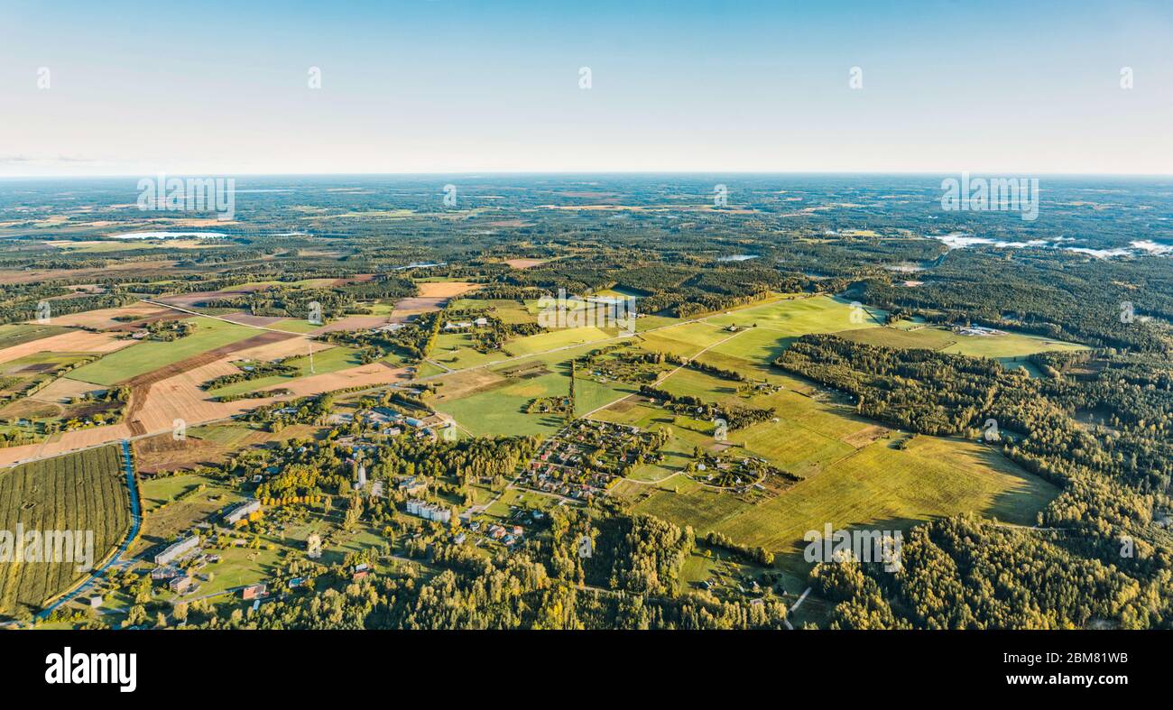 Warme Luft Erdkurve Panoramablick über ländliche Dorf mit Wohn-und Industriegebäude gemischt mit großen Wald, landwirtschaftliche Flächen und blau Stockfoto
