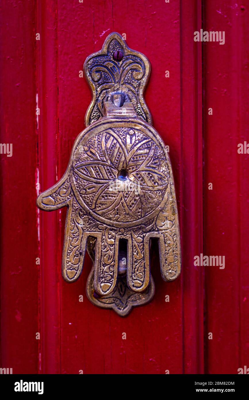 Hand von Fatima, ein typisch marokkanisches Design, als Türklopfer an einer roten Holztür Stockfoto