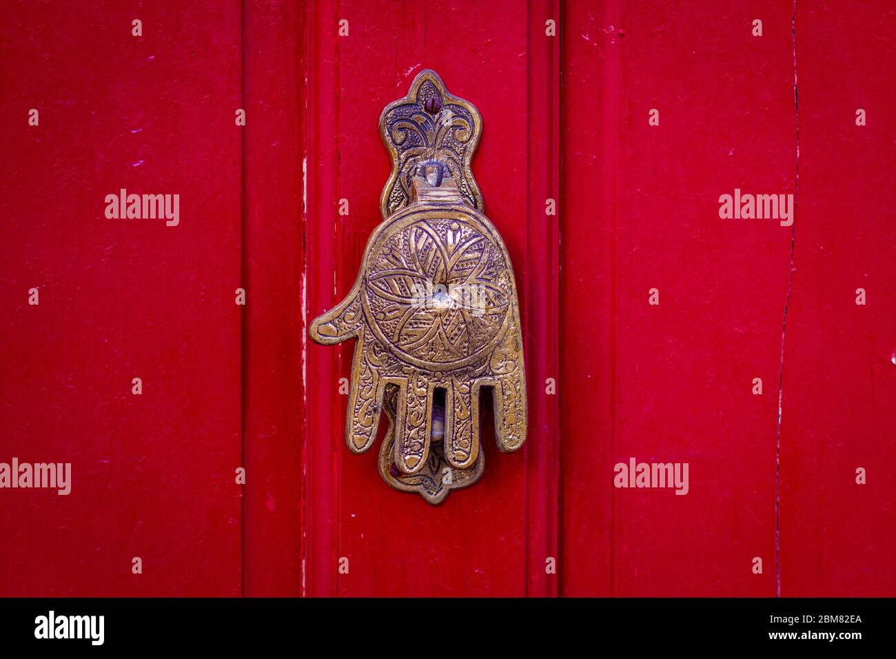 Hand von Fatima, ein typisch marokkanisches Design, als Türklopfer an einer roten Holztür Stockfoto
