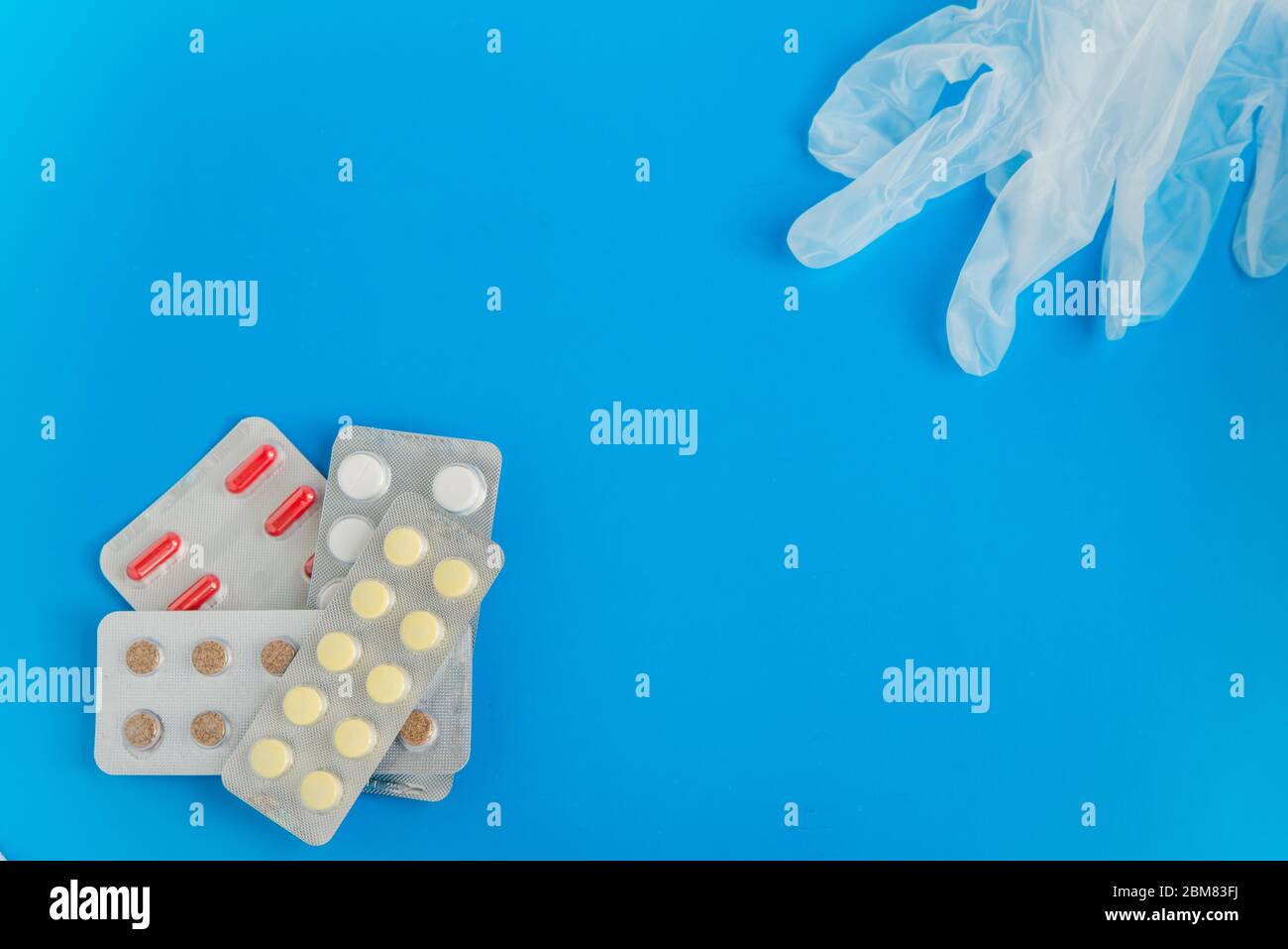 Flache Lage der Pillen Blister-Packs und medizinische Handschuhe auf dem blauen Hintergrund mit Copyspace Stockfoto