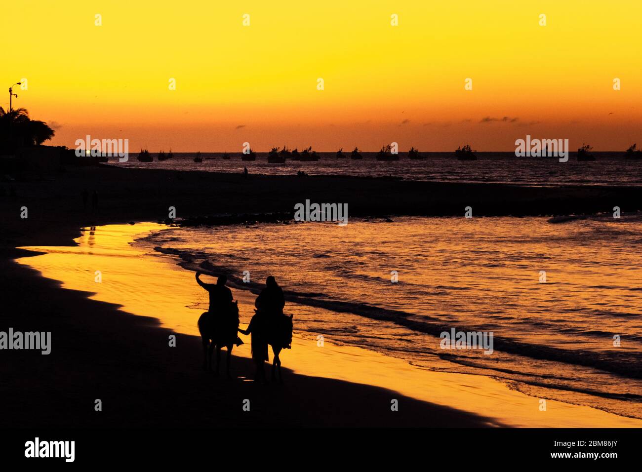 Menschen zu Pferd bei Sonnenuntergang am Strand von Máncora Perú Stockfoto