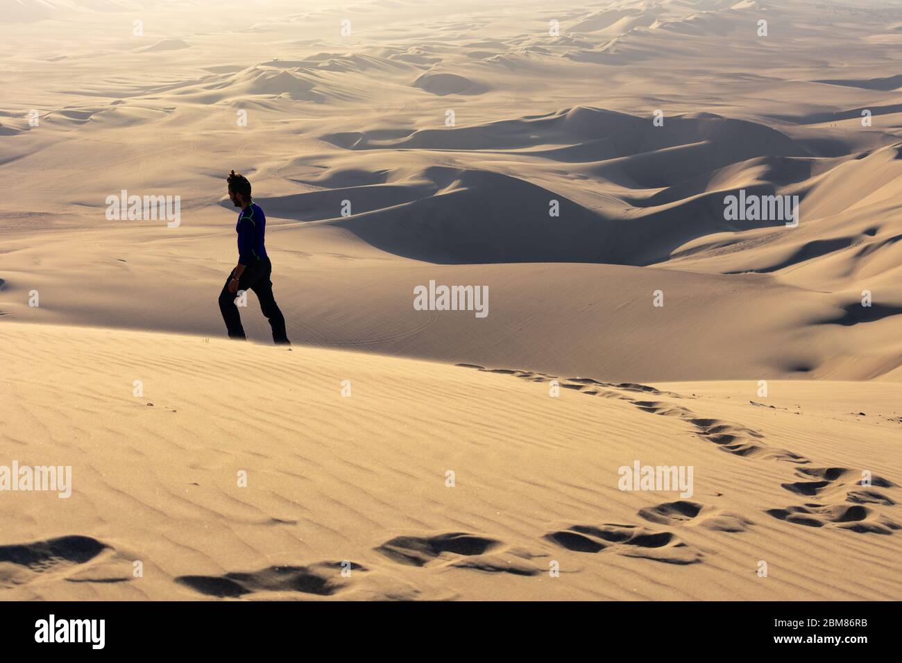 Junger Mann, der auf dem Wüstensand von Huacachina, Peru, verloren ging Stockfoto