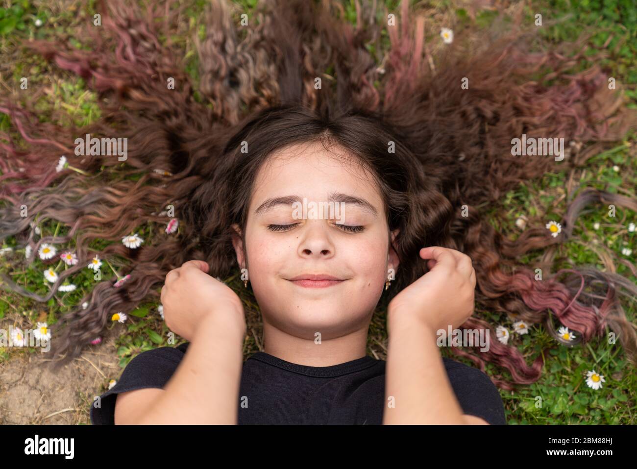 Top Ansicht Foto von einem schönen Brünette lockiges Mädchen mit lockeren Haaren, die auf dem Boden liyes Stockfoto