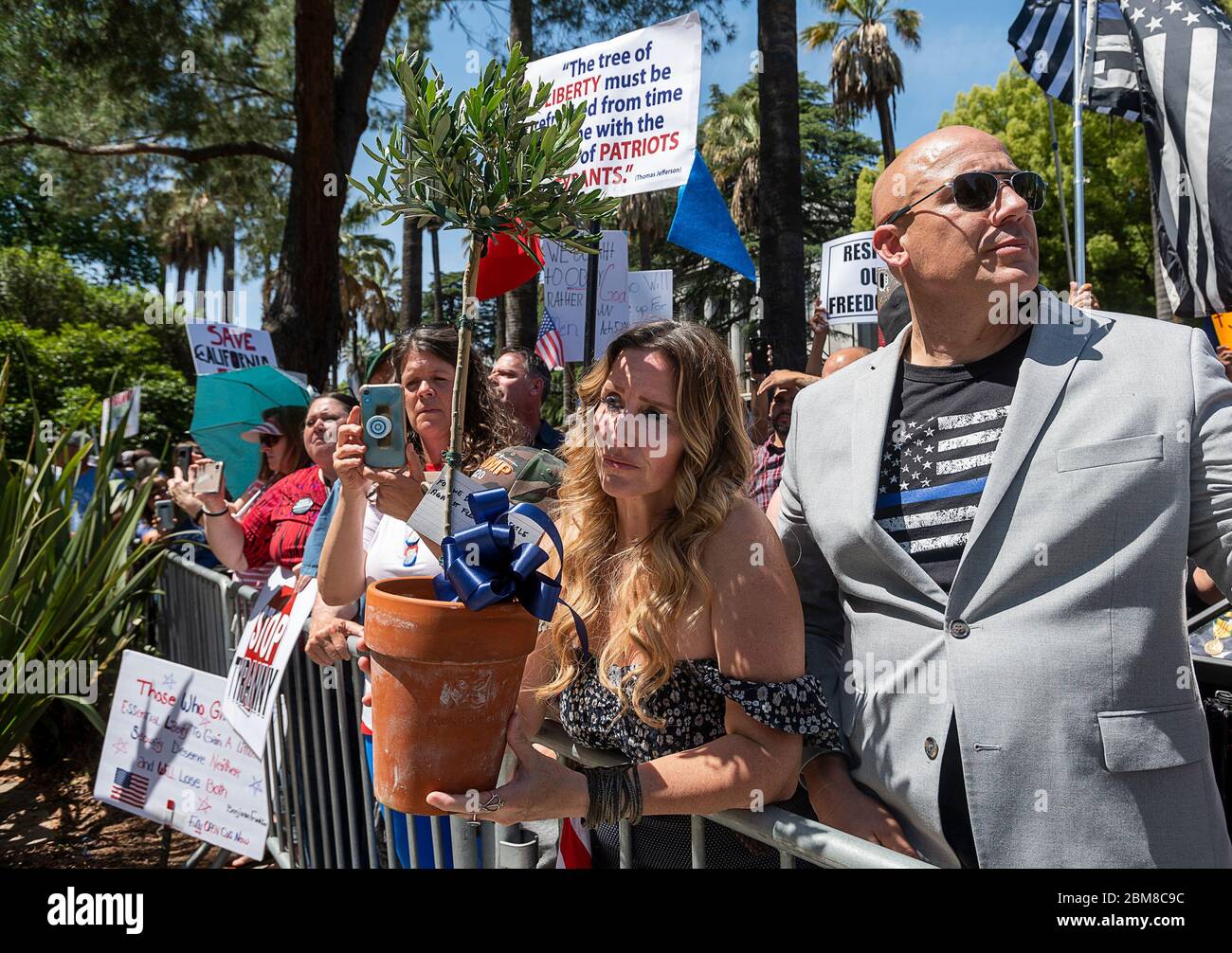 Sacramento, Kalifornien, USA. Mai 2020. Tara Thornton von den Freedom Angels hält einen Olivenbaum für Strafverfolgungsbeamte mit Pastor Tim Thompson während eines Protestes in der Hauptstadt am Donnerstag, 7. Mai 2020 in Sacramento während der Coronavirus-Pandemie. Kredit: Paul Kitagaki Jr./ZUMA Wire/Alamy Live News Stockfoto
