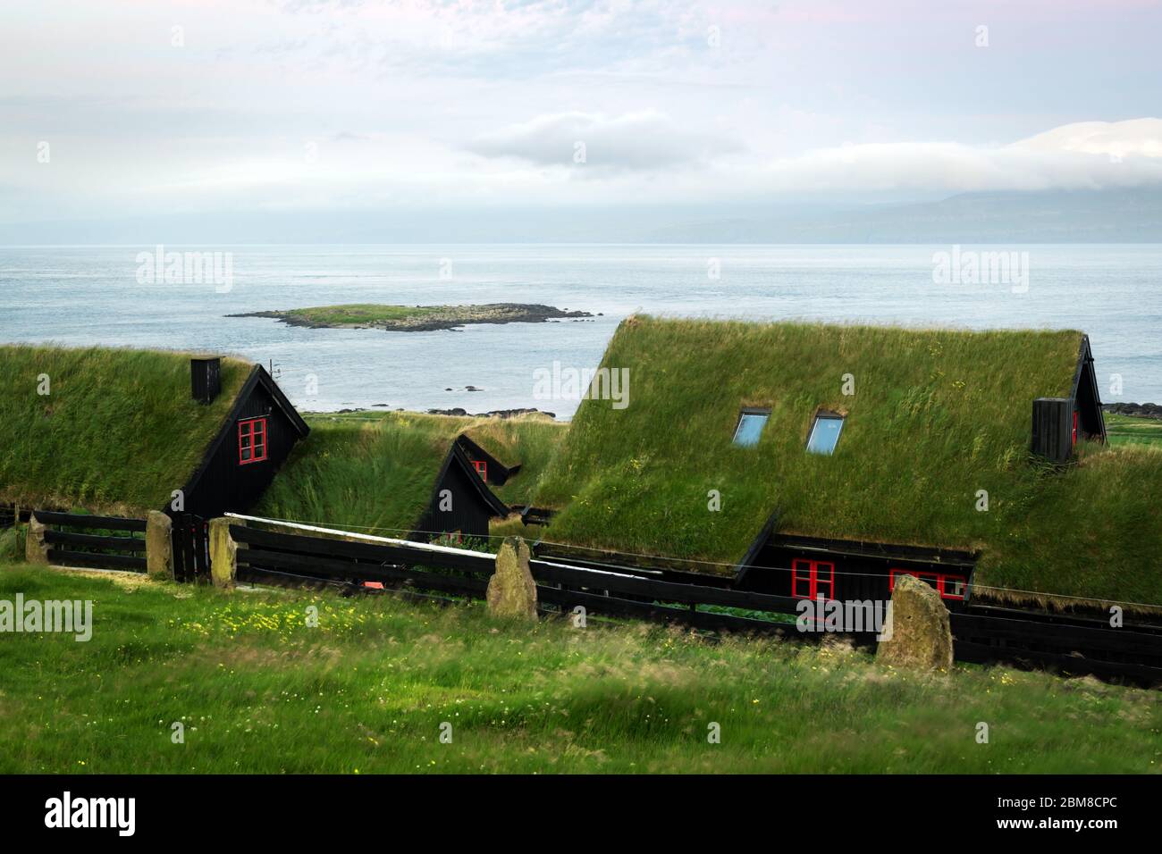 Nebeliger morgen Blick auf ein Haus mit typischer Rasen - top Grasdach und blauen bewölkten Himmel in der Velbastadur Dorf auf Streymoy Island, Färöer, Dänemark. Landschaftsfotografie Stockfoto