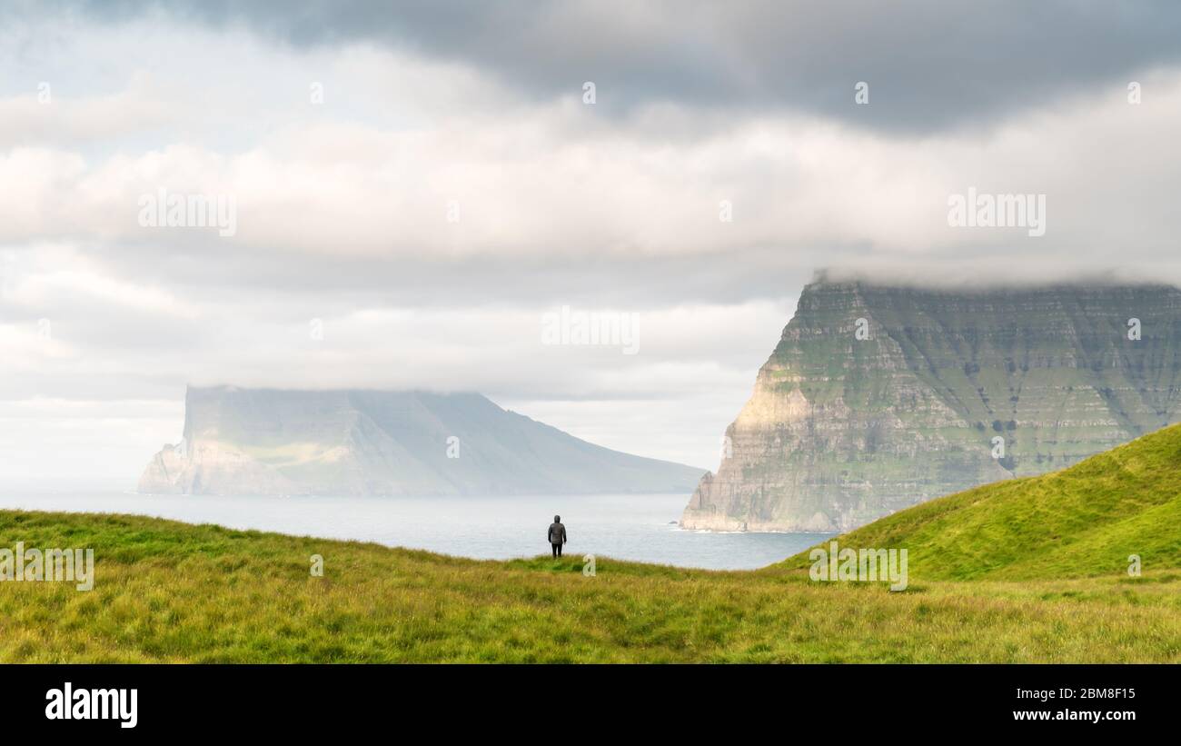Lonely Tourist in der Nähe von kleinen See schaut auf nebligen Inseln im Atlantik von kalsoy Island, Färöer, Dänemark. Landschaftsfotografie Stockfoto
