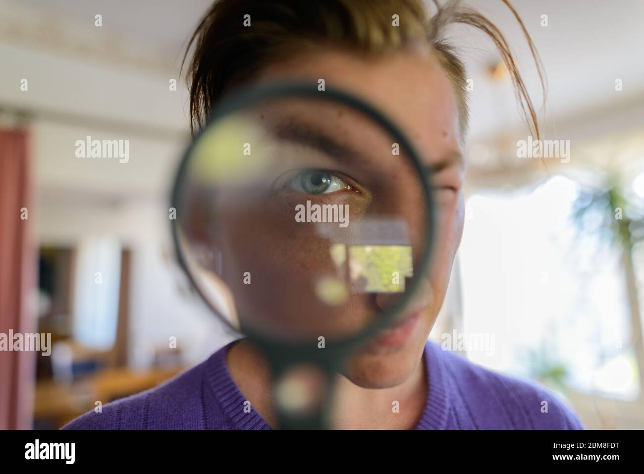Gesicht des jungen Mannes, der durch Lupe schaut Stockfoto