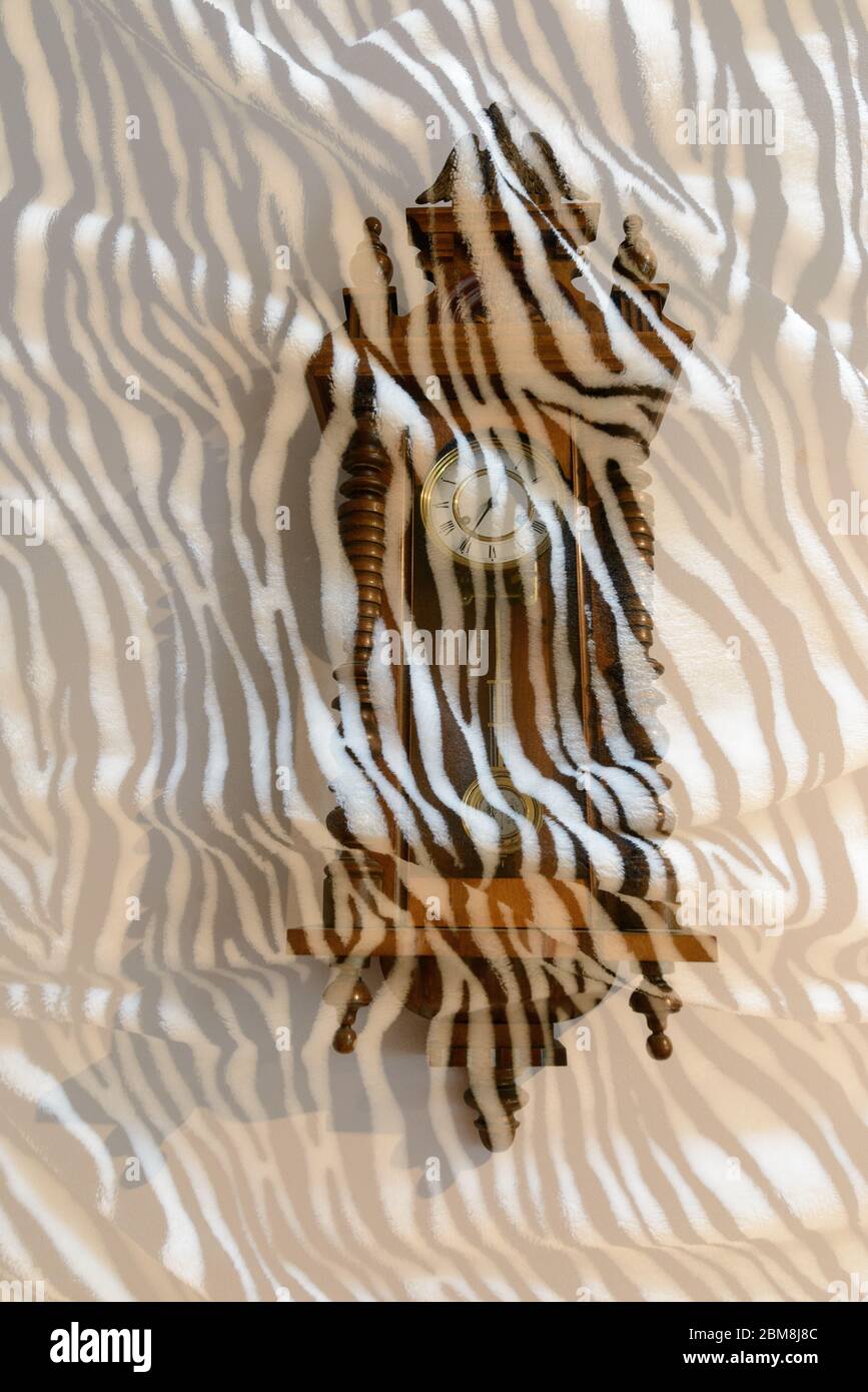 Antike Holzuhr mit überlagerter Bettwäsche und Zebramuster Stockfoto