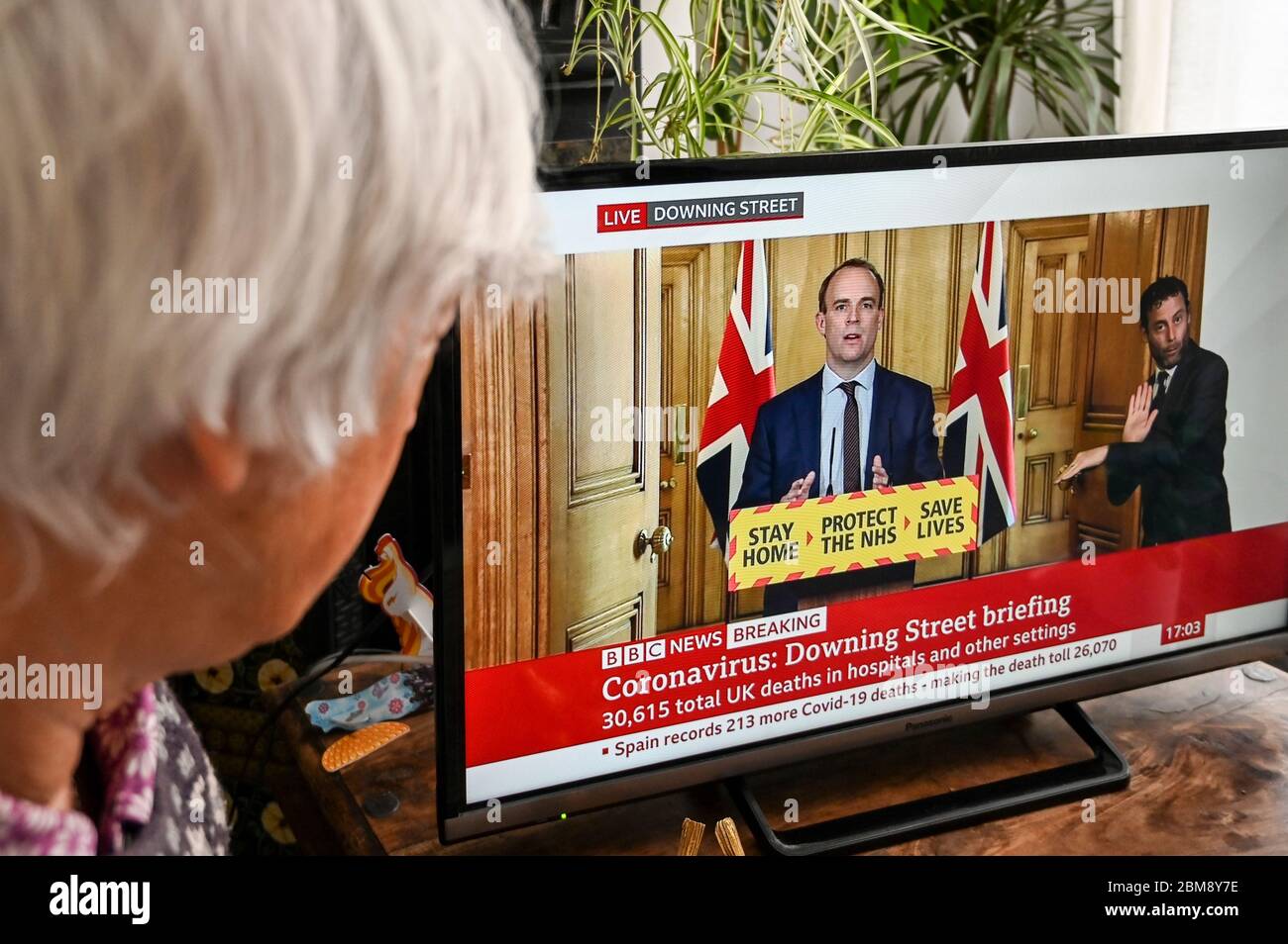 Der stellvertretende Premierminister Dominic Raab gibt das Coronavirus Downing Street Briefing, beobachtet von einem Zuschauer. "Bleib zu Hause, rette den NHS, rette Leben" Banner. Stockfoto