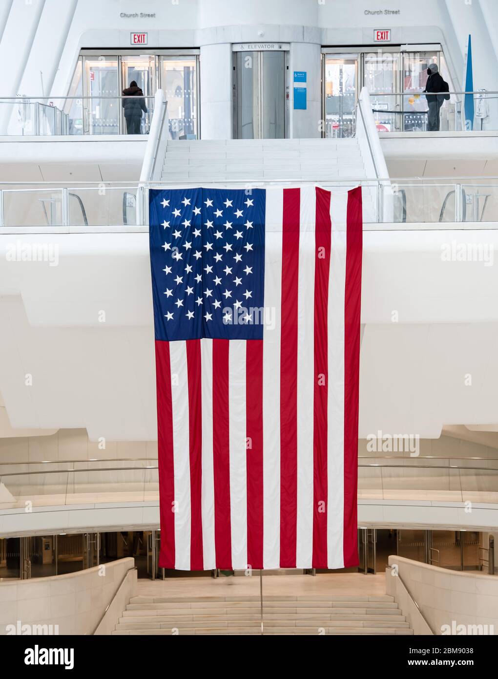 Riesige amerikanische Flagge, die stolz in einem Gebäude in Downtown Manhattan mit U-Bahn-Zugang, in der Nähe des World Trade Center, New York, USA, hängt. Stockfoto