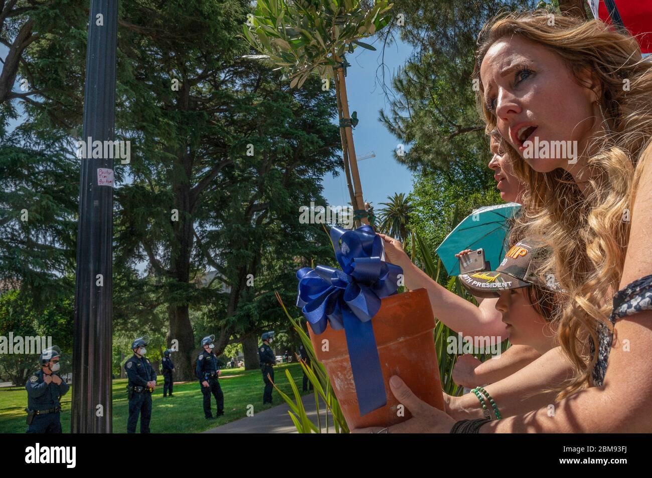 Sacramento, Kalifornien, USA. Mai 2020. Tara Thornton, rechts, von den Freedom Angels hält einen Olivenbaum für Strafverfolgungsbeamte, während eines Protestes vor dem State Capitol am Donnerstag, 7. Mai 2020 in Sacramento während der Coronavirus-Pandemie. Quelle: Renée C. Byer/ZUMA Wire/Alamy Live News Stockfoto