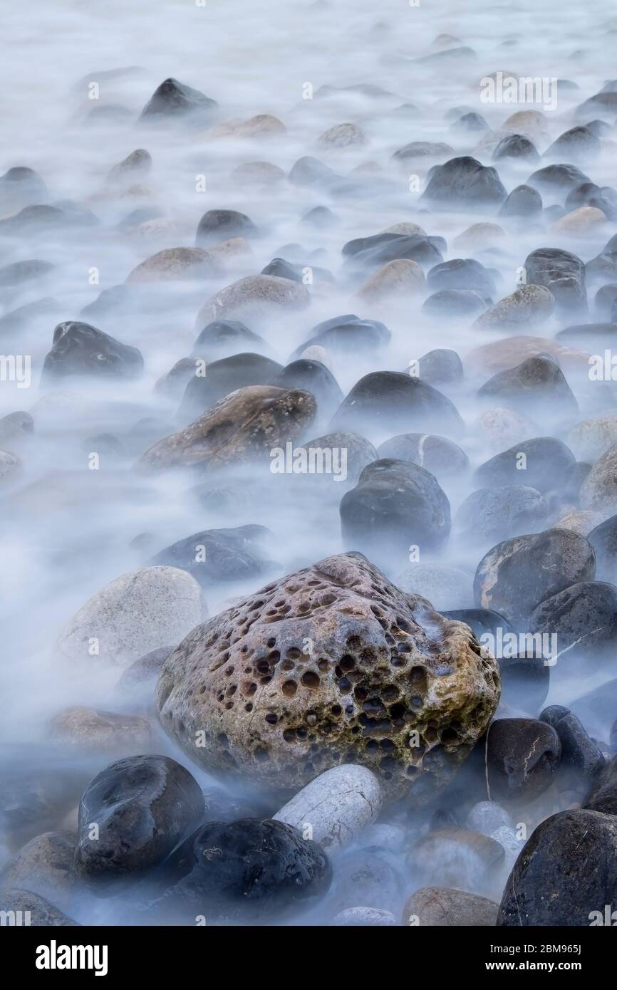 Langzeitbelichtung von Gesteinen, die von der Flut überspült werden, Penmon, Anglesey, North Wales, Großbritannien Stockfoto