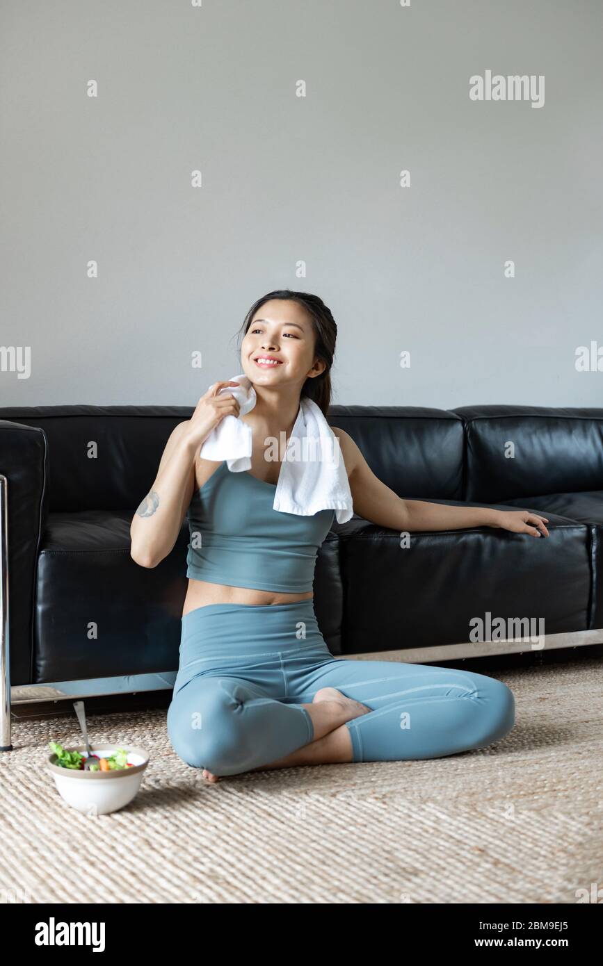 Eine junge Asiatin isst einen gesunden Gemüsesalat im Wohnzimmer Stockfoto