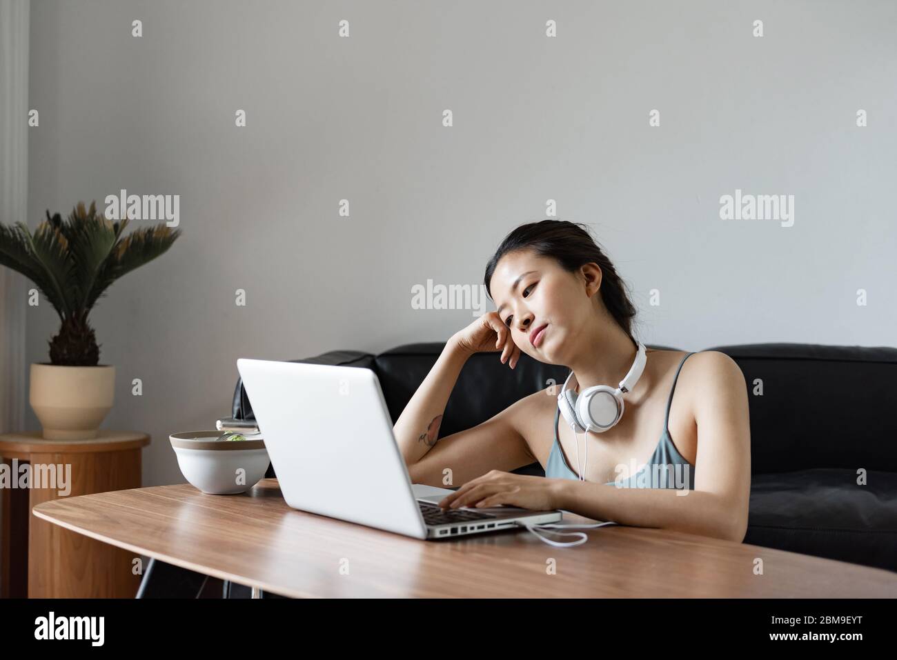 Eine junge Asiatin, die einen Computer im Wohnzimmer benutzt Stockfoto
