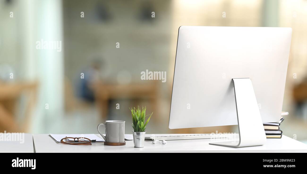 Arbeitsplatz Computer-Monitor setzen auf weißen Schreibtisch und umgeben von Wireless-Tastatur, Stapel von Büchern, Topfpflanze, Kaffeetasse, Gläser und cl Stockfoto