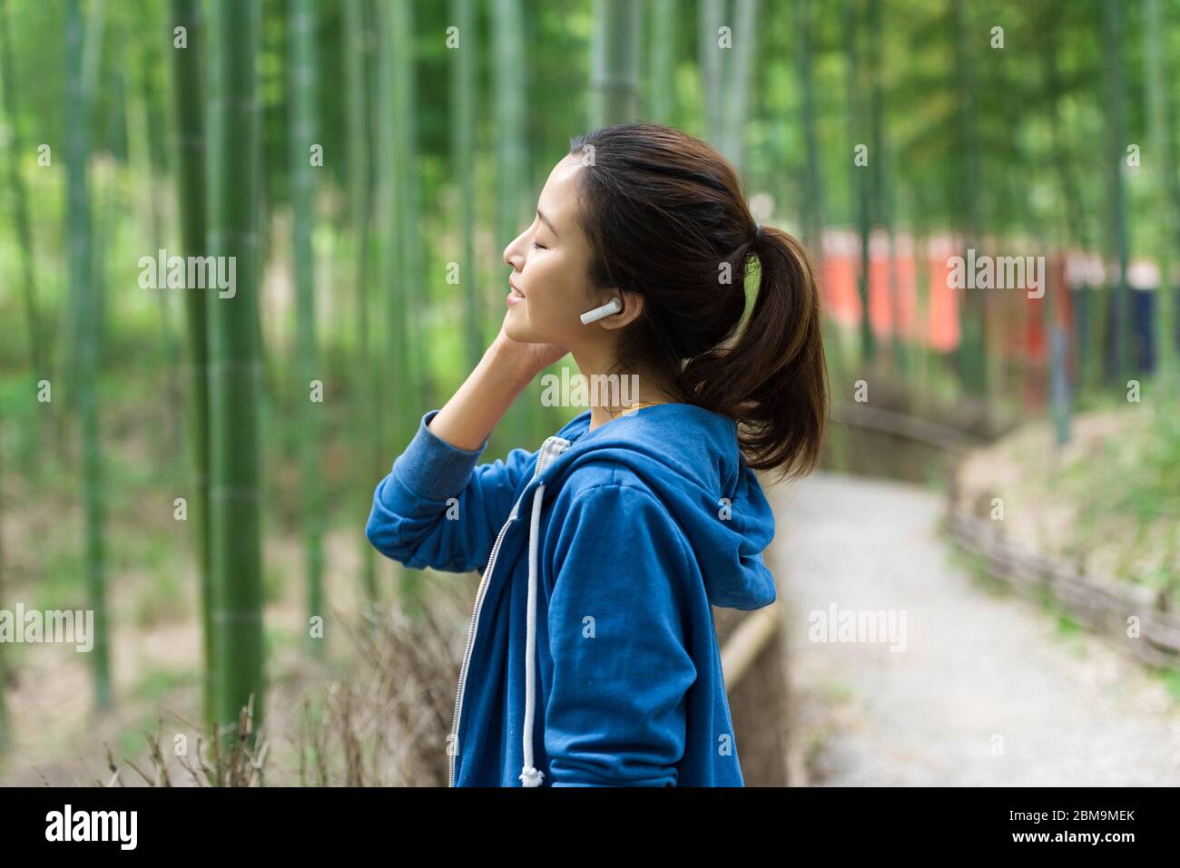 Eine junge Asiatin spaziert und ruht in einem Bambuswald aus Stockfoto
