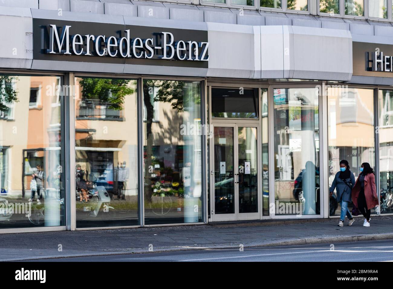 Berlin, Deutschland. Mai 2020. Fußgänger mit Gesichtsmasken laufen an einem Autohaus von Mercedes-Benz in der deutschen Hauptstadt Berlin, 7. Mai 2020, vorbei. Der Autoexport in Deutschland sei "fast zum Stillstand gekommen", so der Verband der Automobilindustrie (VDA). Im April wurden weltweit nur 17,600 neue Pkw an Kunden ausgeliefert, die um 94 Prozent gesunken sind. Kredit: Binh Truong/Xinhua/Alamy Live News Stockfoto