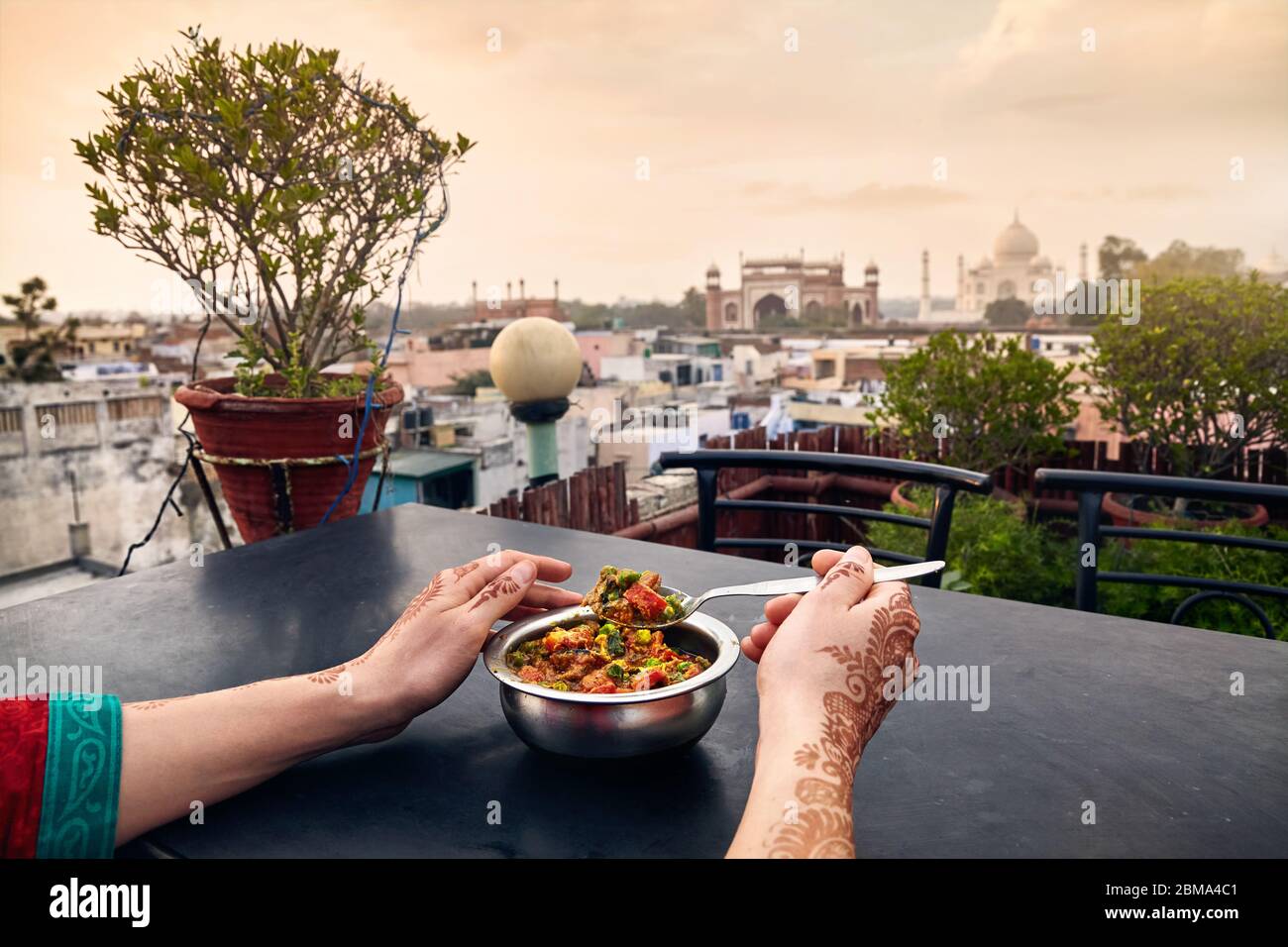 Frau, die traditionelle indische Essen im Restaurant auf der Dachterrasse mit Blick auf Taj Mahal in Agra, Uttar Pradesh, Indien Stockfoto