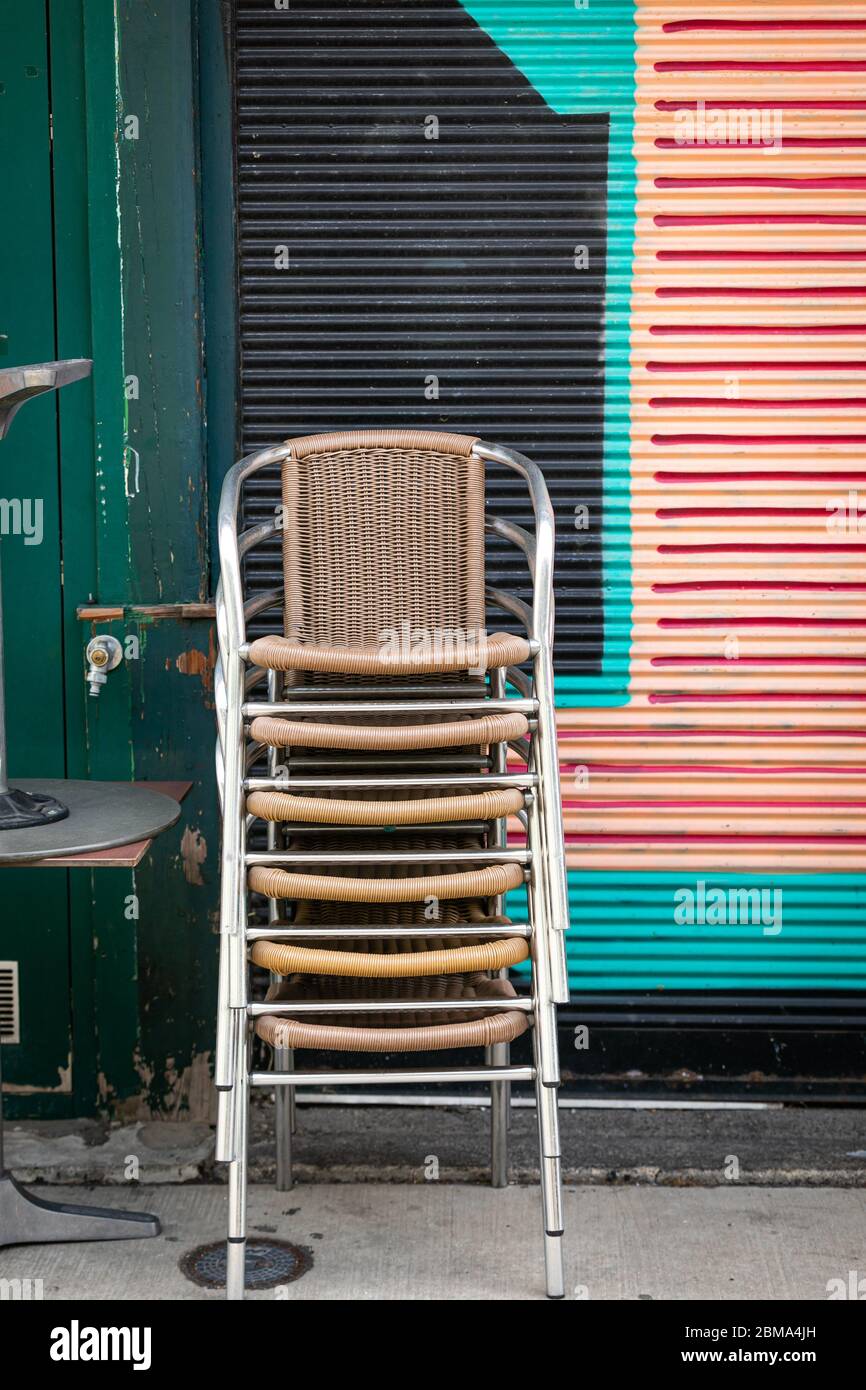 Gestapelte Stühle vor einem geschlossenen Marktstand Stockfoto