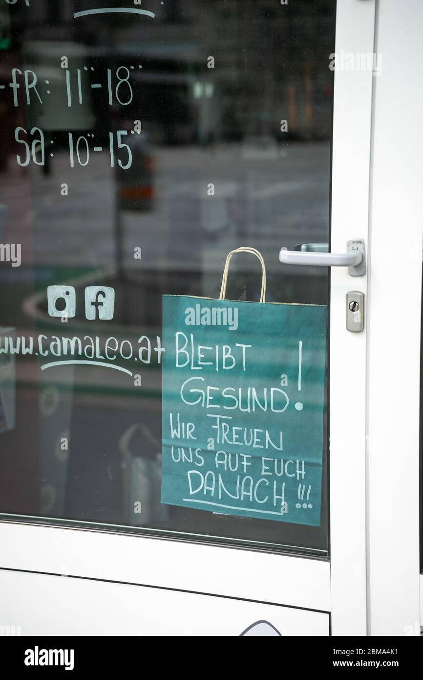 Bleiben Sie gesund Wunsch, geschrieben in deutscher Sprache auf einem Papier-Einkaufstasche und aufgehängt in einem Ladeneingang Stockfoto