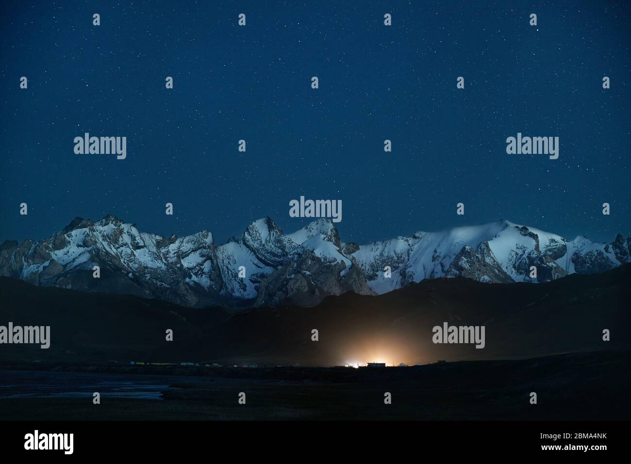 Die schöne Landschaft der weißen Gipfel Berge und glühenden Camp unter Nacht Himmel voller Sterne in der Nähe von Kel Suu See in der naryn Region, Kirgisistan Stockfoto